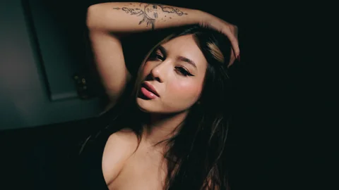 Portrait in a black dress with one hand on the head.