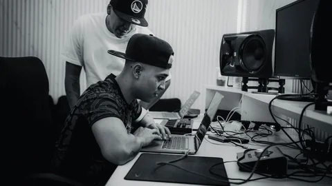 Person working at a computer in a studio, in black and white.