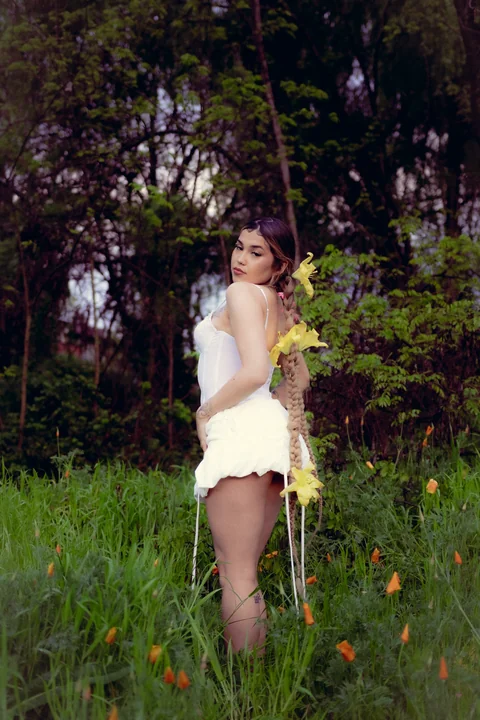 Person dressed in white among greenery.