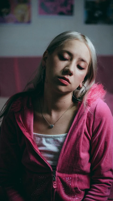 Portrait in a pink jacket in front of a wall of images.