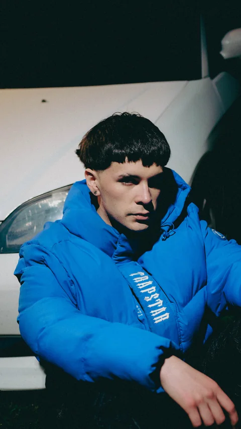 Person in a blue jacket beside a white car.
