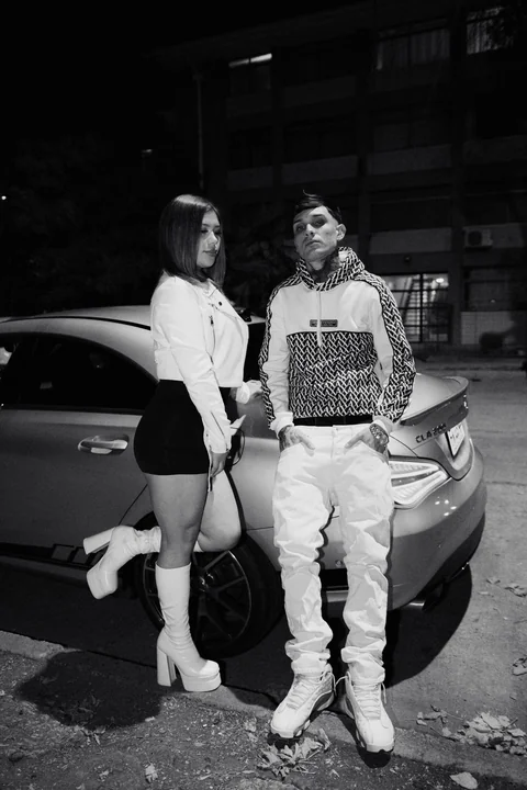 Two people beside a car, in black and white.