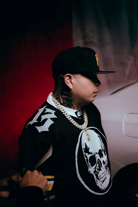 Perfil de una persona con gorra negra y prenda con motivos blancos.
