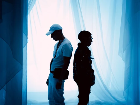 Dos siluetas de perfil frente a telas iluminadas con luz azul.