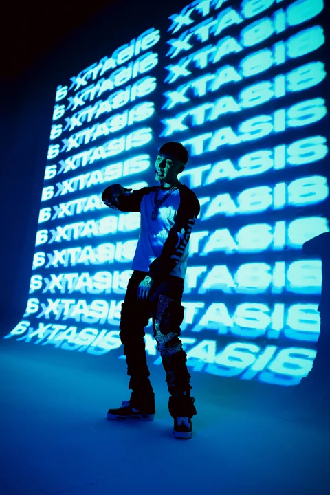 Silueta bajo una proyección de letras azules en un set oscuro.
