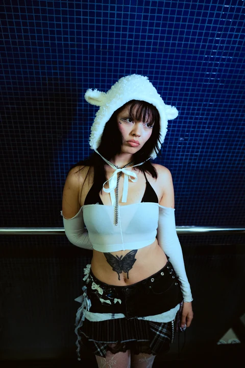 Mujer con gorro blanco y top celeste frente a una pared azul.