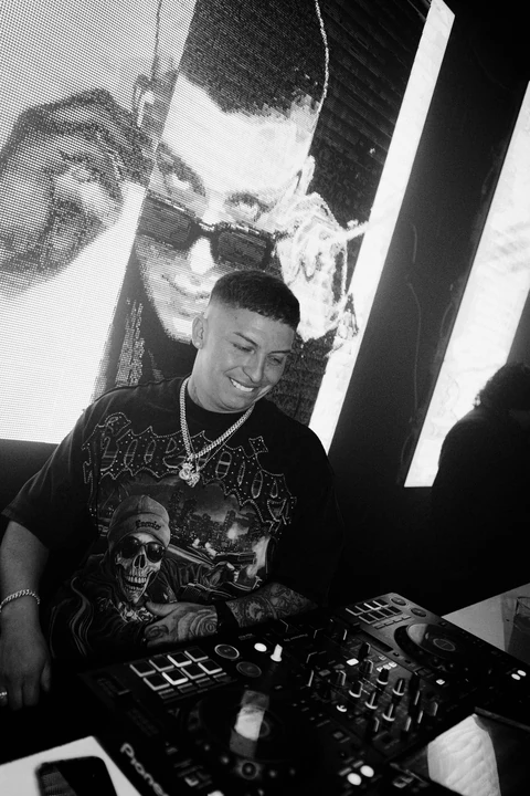 Fotografía en blanco y negro de un DJ con una proyección a su espalda.